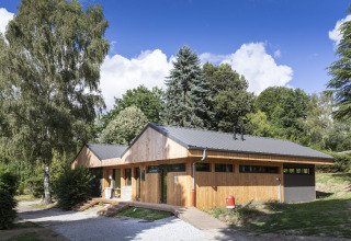 Modern houten gebouw te midden van groen in vakantiedomein Huttopia Lac de la Siauve, Auvergne-Rhône-Alpes.