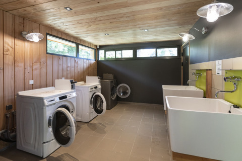 Laundry room with washing machines and large sinks at Huttopia Lac de la Siauve, holiday park in Auvergne-Rhône-Alpes, France.