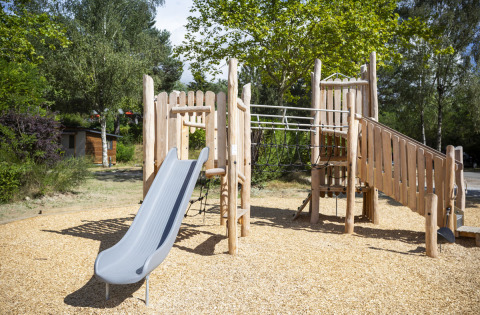 Parque infantil de madera con tobogán y escalera en Huttopia Lac de la Siauve, Auvergne-Rhône-Alpes, Francia.