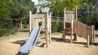 Parque infantil de madera con tobogán y escalera en Huttopia Lac de la Siauve, Auvergne-Rhône-Alpes, Francia.