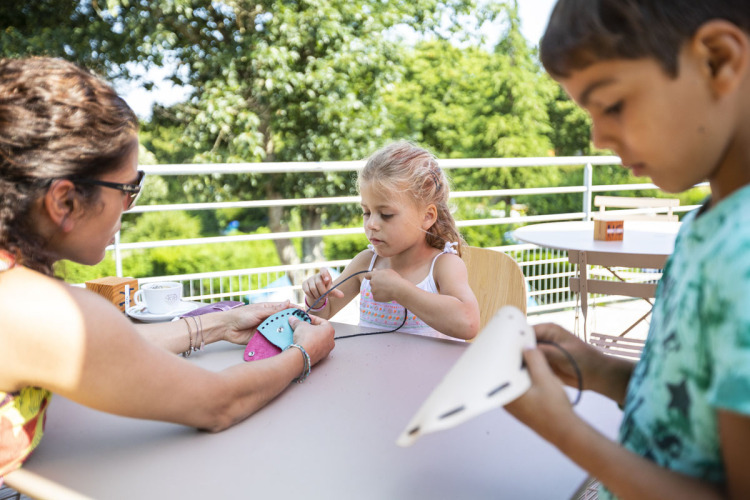 Children and adult doing crafts together at a table at Huttopia Lac de la Siauve, Auvergne-Rhône-Alpes, France.