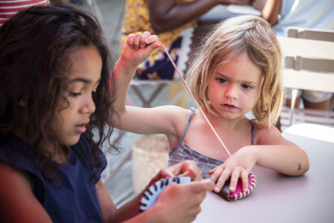 Twee kinderen knutselen samen aan een tafel op Huttopia Lac de la Siauve vakantiepark in Frankrijk.