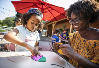 A child and a woman doing crafts together at a table in Huttopia Lac de la Siauve holiday park, France.
