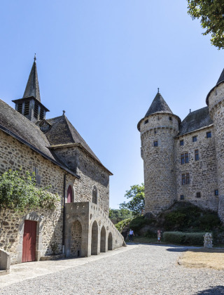 Fotografía de un castillo medieval y una iglesia cerca de Lanobre, Auvernia-Ródano-Alpes, Francia, con torres.