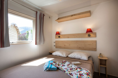 Gemütliches Schlafzimmer im Gypsy Caravan bei Huttopia le Moulin, Frankreich, mit Doppelbett und Fenster.