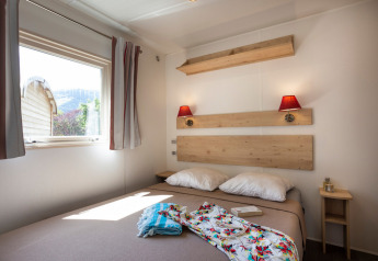 Gemütliches Schlafzimmer im Gypsy Caravan bei Huttopia le Moulin, Frankreich, mit Doppelbett und Fenster.