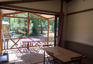 Vista interior del Chalet Evasion en Huttopia le Moulin, Francia, con terraza, mesa y sillas.