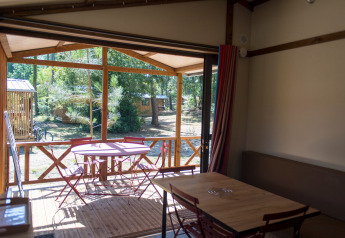 Indvendigt syn af Chalet Evasion på Huttopia le Moulin i Frankrig med terrasse, bord og stole.