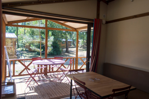 Indvendigt syn af Chalet Evasion på Huttopia le Moulin i Frankrig med terrasse, bord og stole.