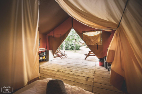 Vista interna di una tenda safari chiamata Tent Saadani a Huttopia Vallée du Lot in Francia con terrazza in legno.