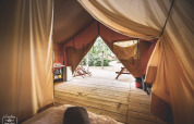 Vista interna di una tenda safari chiamata Tent Saadani a Huttopia Vallée du Lot in Francia con terrazza in legno.