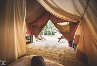 Vue intérieure d'une tente safari nommée Tent Saadani à Huttopia Vallée du Lot en France avec terrasse en bois.