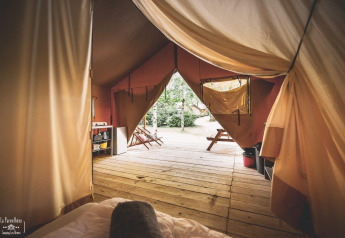 Vista interna di una tenda safari chiamata Tent Saadani a Huttopia Vallée du Lot in Francia con terrazza in legno.