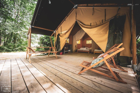 Safaritent Tent Saadani bij Huttopia Vallée du Lot in Frankrijk, met houten terras en loungestoelen buiten.