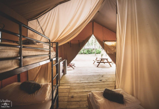 Interiør af safari teltet Saadani ved Huttopia Vallée du Lot i Frankrig med køjesenge og terrasse.
