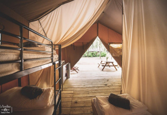 Interno della tenda safari Saadani a Huttopia Vallée du Lot in Francia, con letti a castello e veranda in legno.