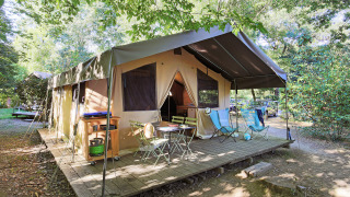 Safari Sweet Tent mit Holzterrasse und Gartenmöbeln, umgeben von Bäumen und Autos im Hintergrund.