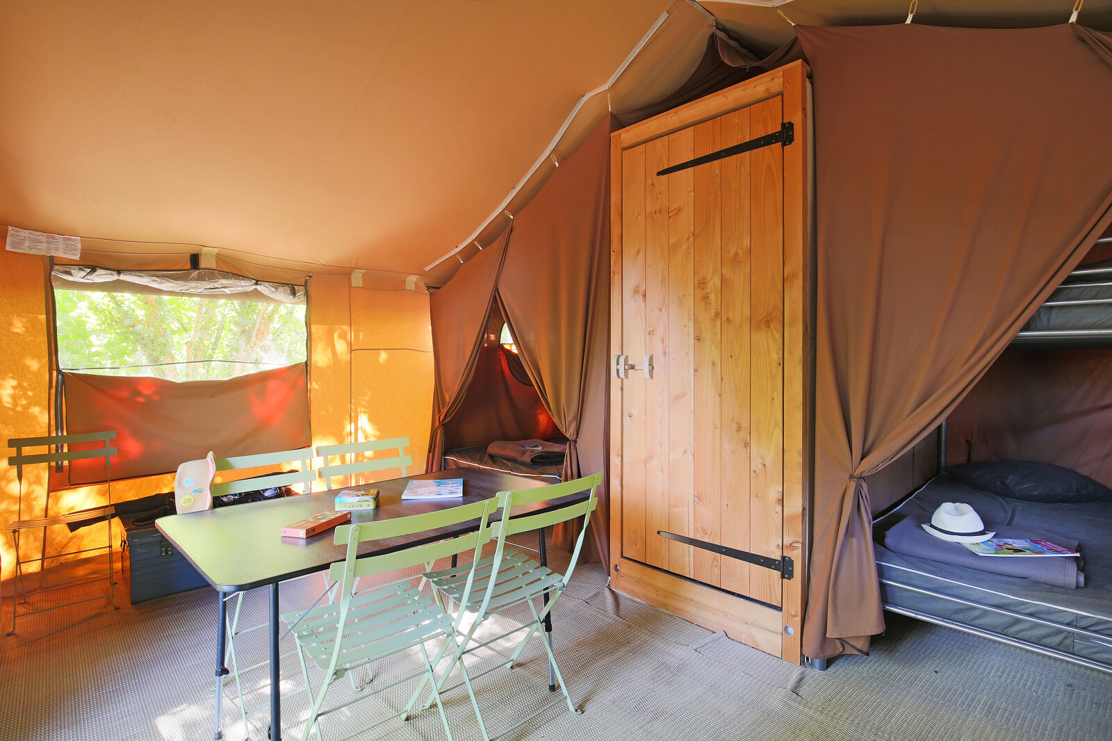 Interieur van een Sweet Tent safaritent bij Huttopia Vallée du Lot, Frankrijk, met tafel en bedden.