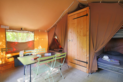 Interno di una tenda safari Sweet Tent presso Huttopia Vallée du Lot, Francia, con tavolo e letti.