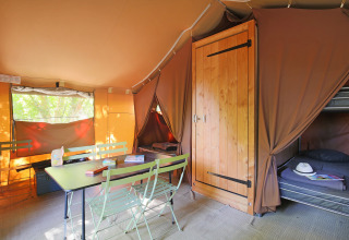 Interno di una tenda safari Sweet Tent presso Huttopia Vallée du Lot, Francia, con tavolo e letti.