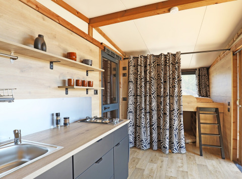 Interior of Arizona safari tent at Huttopia Vallée du Lot, France, featuring a modern kitchen and bunk bed.