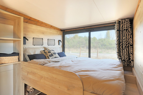 Acogedor dormitorio en la tienda safari Arizona de Huttopia Vallée du Lot, Francia, con vista al exterior.