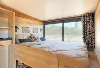 Acogedor dormitorio en la tienda safari Arizona de Huttopia Vallée du Lot, Francia, con vista al exterior.
