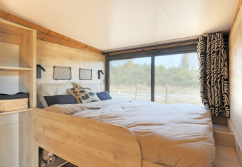 Acogedor dormitorio en la tienda safari Arizona de Huttopia Vallée du Lot, Francia, con vista al exterior.