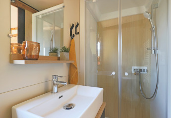 Bagno moderno nella tenda safari Arizona a Huttopia Vallée du Lot, Francia, con doccia e lavandino.
