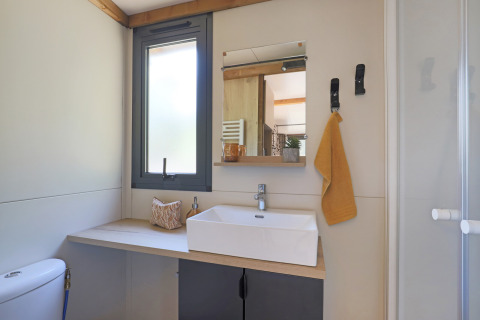 Baño moderno en una tienda safari Arizona de Huttopia Vallée du Lot, Francia, con lavabo y espejo visibles.
