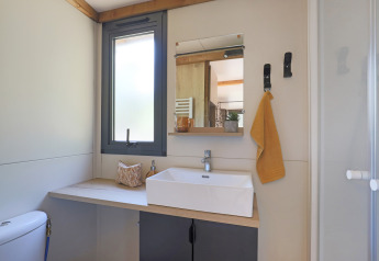Bagno moderno in una tenda safari Arizona a Huttopia Vallée du Lot, Francia, con lavabo e specchio presenti.