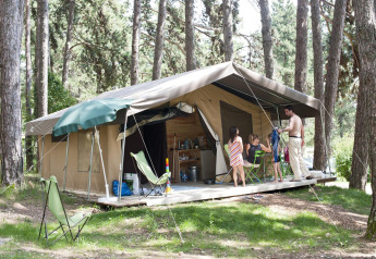Familie nyder camping foran en safari telt i skovene ved Huttopia Divonne Les Bains, Frankrig.