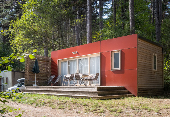 Casa móvil Vancouver: Moderna cabaña de madera con detalles rojos y terraza, situada en un bosque.