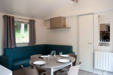 Zona pranzo nella Mobile home Vancouver a Huttopia Divonne Les Bains, Francia, con arredi moderni.