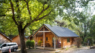 Chalet Montana, een houten blokhut met veranda, omgeven door groene bomen in een bosrijke omgeving.