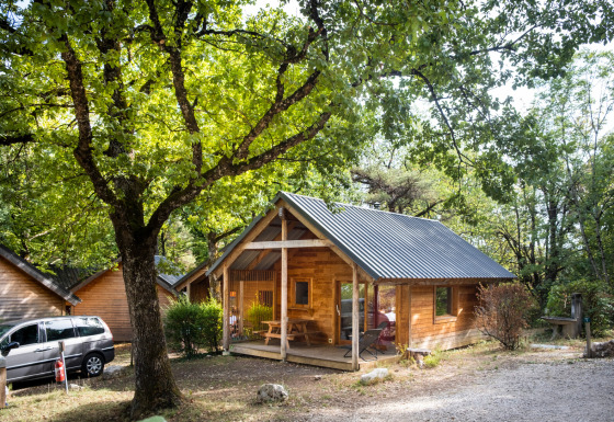 Chalet Montana, een houten blokhut met veranda, omgeven door groene bomen in een bosrijke omgeving.