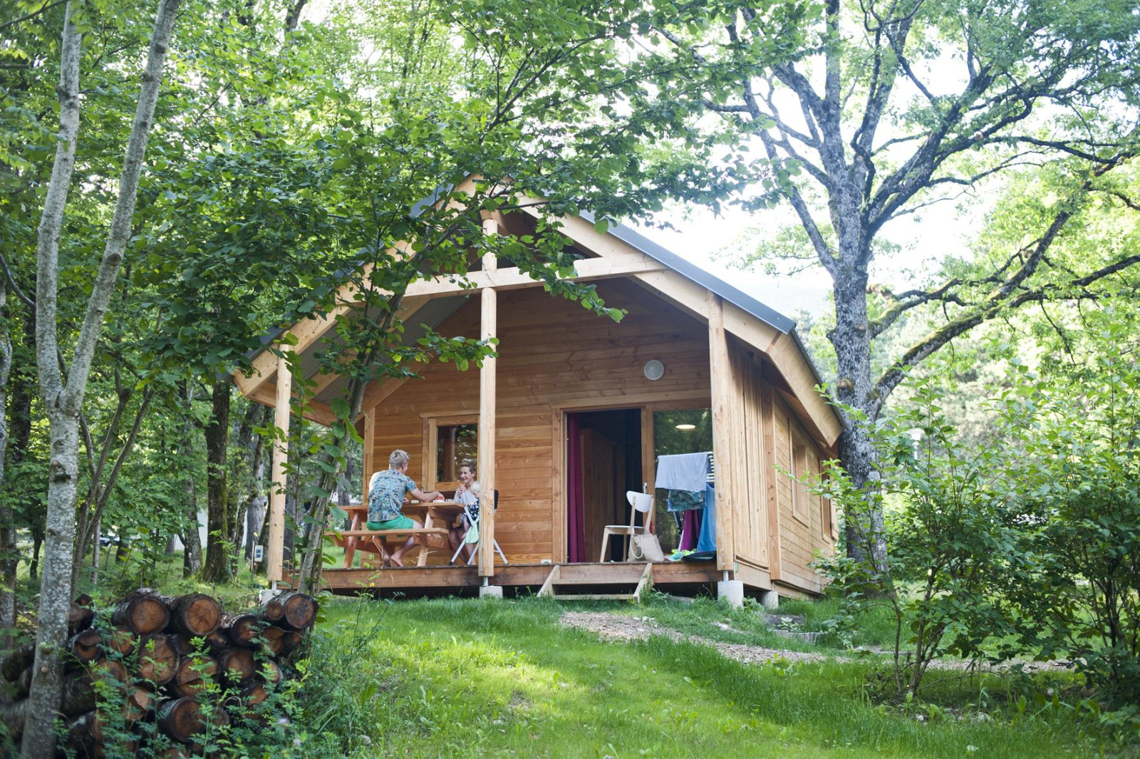 Twee mensen zitten aan een tafel op de veranda van Chalet Montana bij Huttopia Divonne Les Bains in Frankrijk.