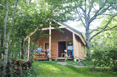 Twee mensen zitten aan een tafel op de veranda van Chalet Montana bij Huttopia Divonne Les Bains in Frankrijk.