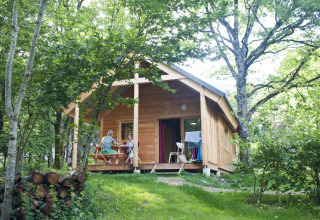 Zwei Menschen sitzen an einem Tisch auf der Veranda der Chalet Montana Hütte bei Huttopia Divonne Les Bains.