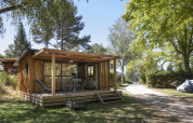 Vista frontal del Chalet Evasion con terraza de madera y muebles, rodeado de árboles en un entorno tranquilo.