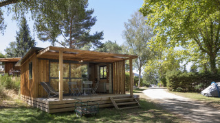 Vista frontal del Chalet Evasion con terraza de madera y muebles, rodeado de árboles en un entorno tranquilo.