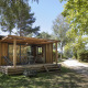 Chalet Evasion set fra forsiden med terrasse og havemøbler, omgivet af træer i et roligt naturområde.