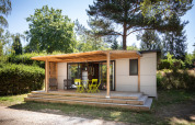 Mobile home Vancouver per glamping con terrazza in legno e mobili da giardino immersa nel verde.