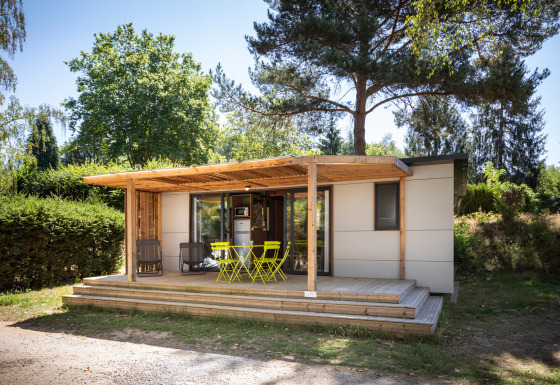 Glampingverblijf Mobile home Vancouver met houten terras en opvallend meubilair tussen bomen.