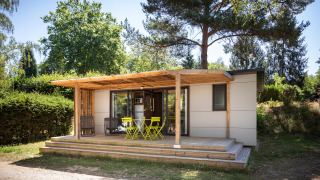 Glamping-Unterkunft Mobile Home Vancouver mit Holzterrasse und Gartenmöbeln in grüner Natur.