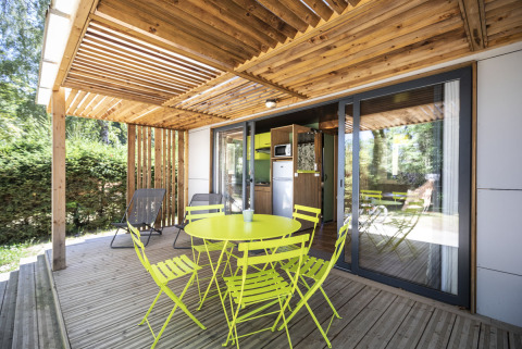 Überdachte Terrasse mit gelbem Gartenmöbelset am Mobile home Vancouver, Huttopia Lac de la Siauve, Frankreich.