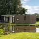 Moderne lodge The Water Lily ved en rolig dam i Holiday Park De Lochemse Berg, Holland, omringet af natur.