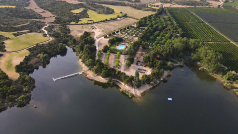 Vista aérea del parque vacacional TAIGA Lake Caspe en Aragón, España, con lago, bosque y piscina.