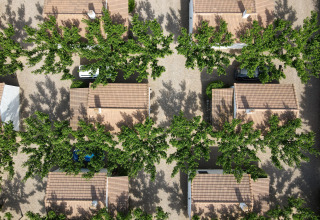 Luchtbeeld van vakantiewoningen en bomen in TAIGA Lake Caspe park, Aragón, Spanje, met schaduwen in de zon.