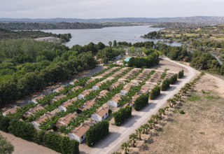 Vista aerea del villaggio TAIGA Lake Caspe in Aragona, Spagna, con bungalow immersi nel verde vicino al lago.